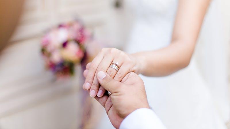 Mains d'un couple se tenant avec alliances